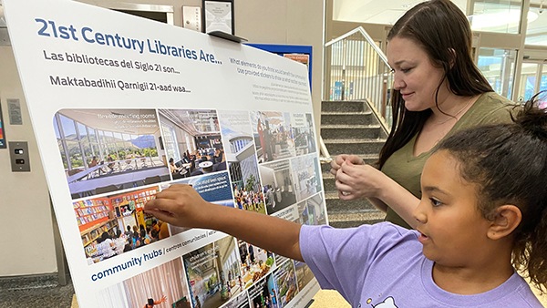 two customers placing stickers on a 21st century library engagement board