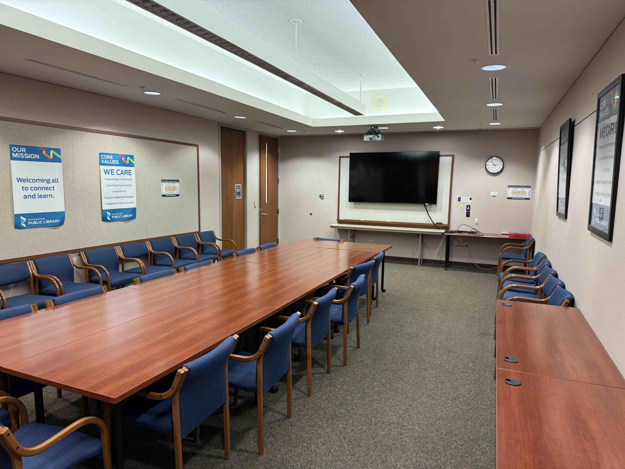 2nd floor meeting room with tables, chairs, and LCD screen